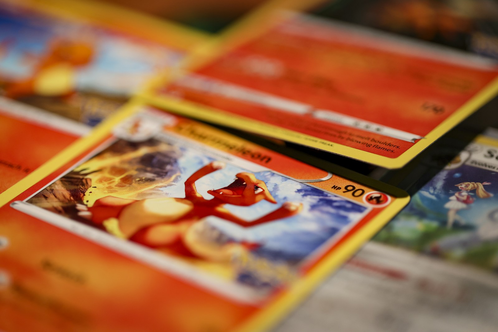Primo piano di carte Pokémon inglesi sovrapposte, con una carta di Charizard in primo piano